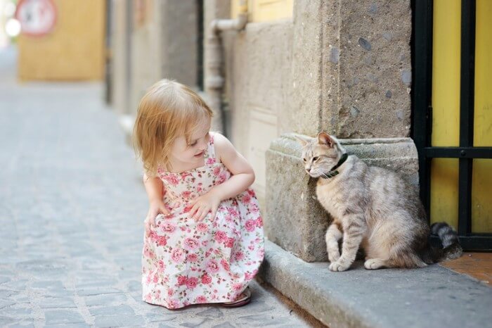 petite fille à l'extérieur saluant un chat